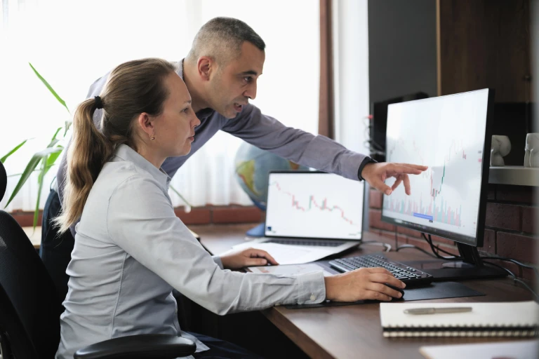 Businessperson helping a co-worker with a task on their computer