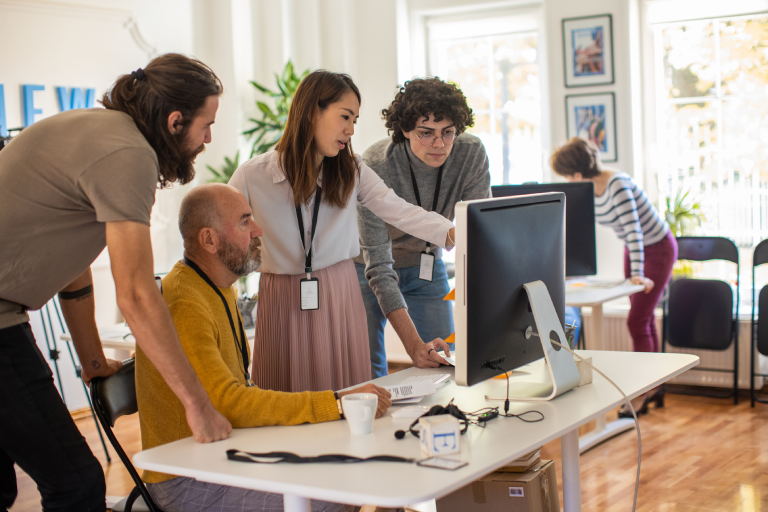 Four office workers looking at a computer monitor