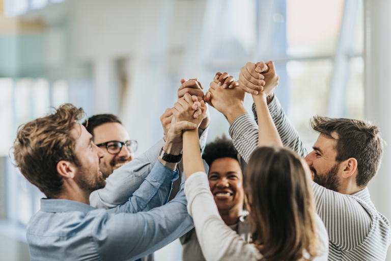 happy coworkers joining hands together in the office